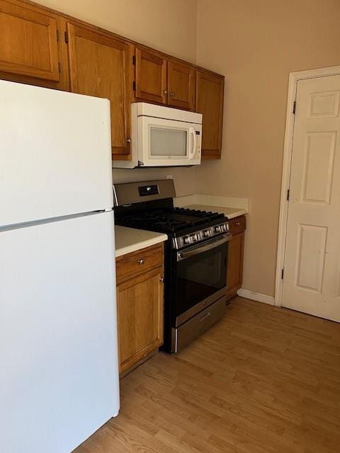 kitchen featuring white appliances, brown cabinets, light wood-style floors, and light countertops