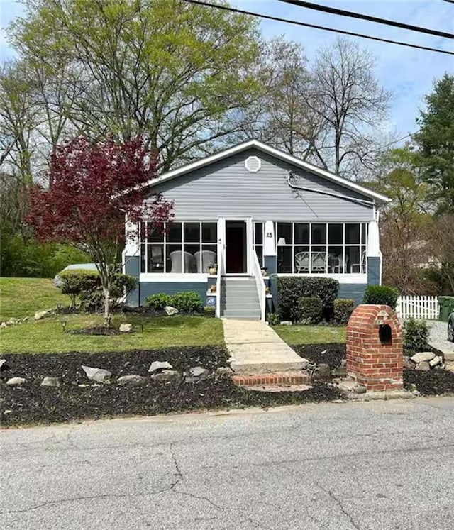 view of front of property with a sunroom and a front lawn