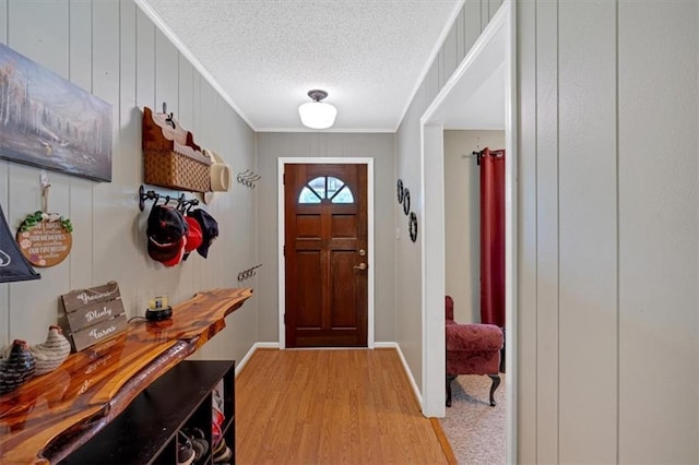 foyer entrance with ornamental molding, light hardwood / wood-style floors, and a textured ceiling