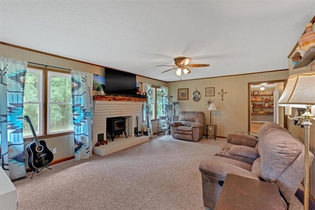 carpeted living room featuring crown molding, a wealth of natural light, ceiling fan, and wood walls