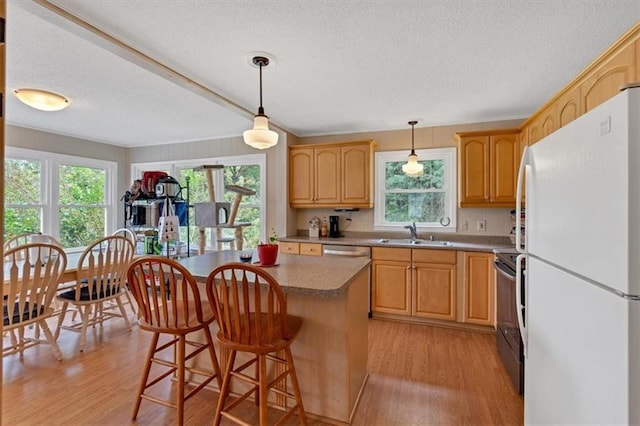 kitchen with a kitchen island, a breakfast bar, sink, white fridge, and electric range