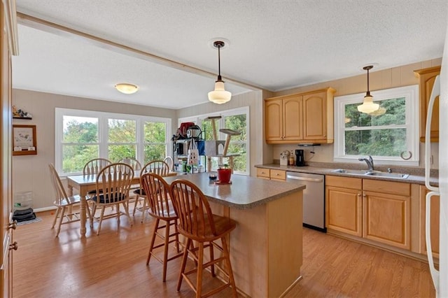 kitchen featuring dishwasher, sink, hanging light fixtures, a center island, and light wood-type flooring