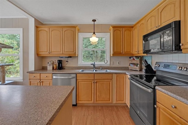 kitchen featuring sink, hanging light fixtures, ornamental molding, appliances with stainless steel finishes, and light hardwood / wood-style floors