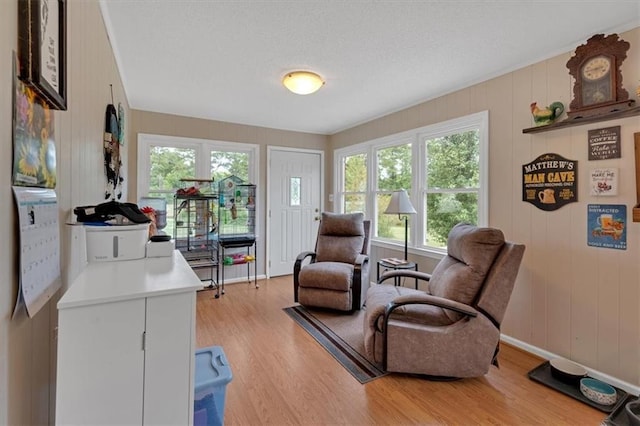 living area featuring a textured ceiling, light hardwood / wood-style floors, and wood walls