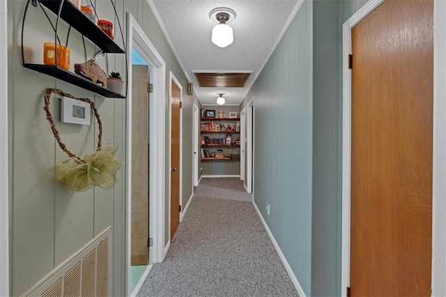 corridor with crown molding, light carpet, built in features, and a textured ceiling