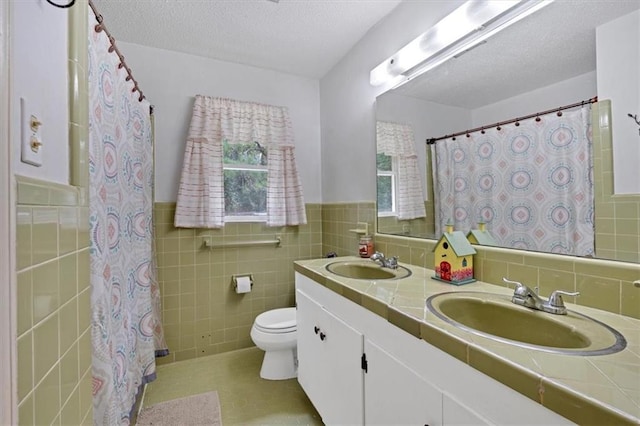 bathroom with vanity, tile walls, a textured ceiling, and toilet