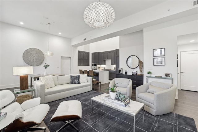 living area featuring visible vents, dark wood-style floors, a high ceiling, a chandelier, and recessed lighting