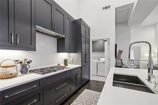 kitchen featuring a sink, visible vents, washer and dryer, light countertops, and stainless steel gas stovetop