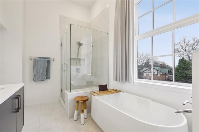 full bathroom with marble finish floor, a freestanding bath, a stall shower, vanity, and baseboards