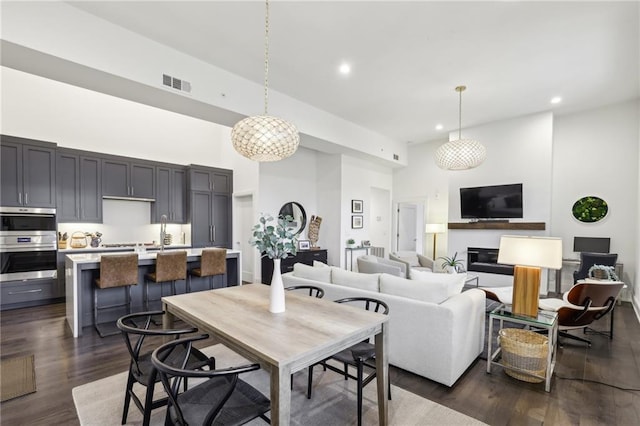 living area featuring recessed lighting, visible vents, dark wood finished floors, and a high ceiling