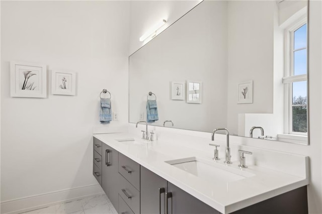 bathroom featuring marble finish floor, a sink, baseboards, and double vanity