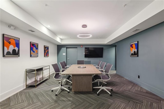 carpeted home office featuring a tray ceiling, visible vents, and baseboards