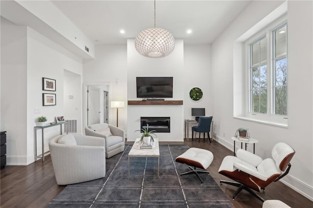 living area with a glass covered fireplace, recessed lighting, baseboards, and wood finished floors