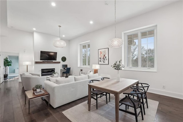 living area with dark wood-type flooring, a glass covered fireplace, baseboards, and recessed lighting