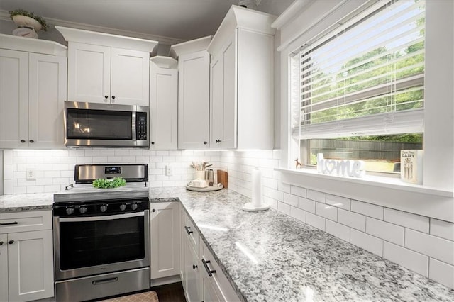 2103 Sourwood Ct, Monroe, GA 30656 - kitchen with appliances with stainless steel finishes, white cabinets, backsplash, and light stone countertops