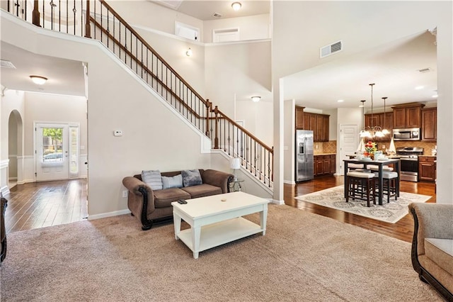 7946 White Oak Loop, Stonecrest, GA 30038 - living area with a towering ceiling, stairs, arched walkways, wood finished floors, and baseboards