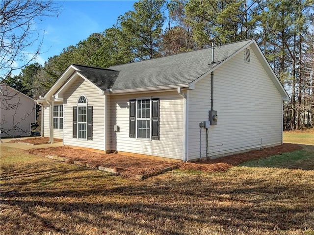 view of side of home featuring a yard and a shingled roof