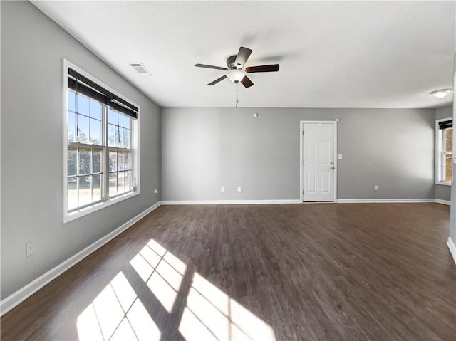 unfurnished living room with visible vents, baseboards, and dark wood-style floors