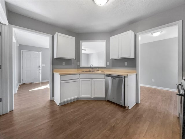 kitchen featuring dark wood-style floors, white cabinetry, a sink, light countertops, and dishwasher