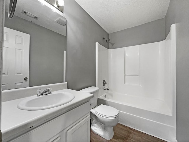 full bathroom with toilet, a textured ceiling, wood finished floors,  shower combination, and vanity