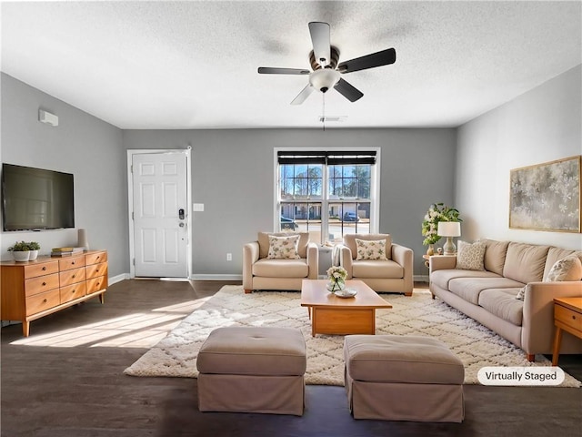 living area featuring a textured ceiling, a ceiling fan, baseboards, and wood finished floors