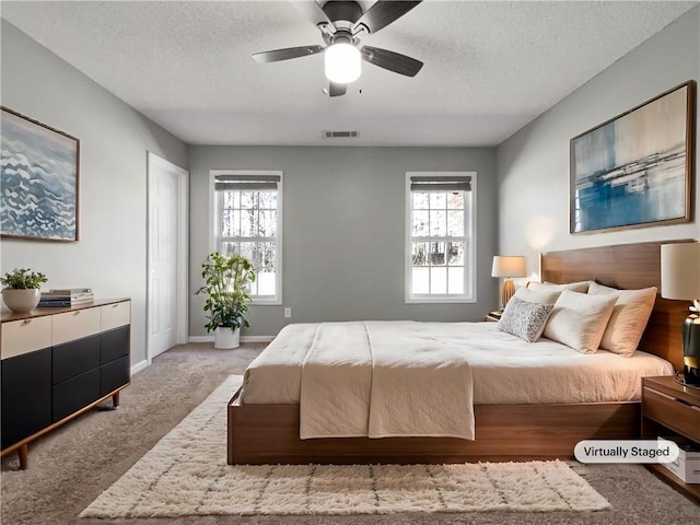 carpeted bedroom with visible vents, ceiling fan, a textured ceiling, and baseboards