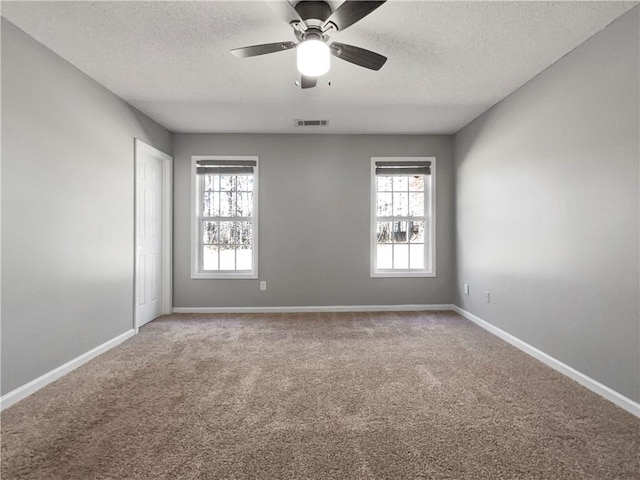 unfurnished room with visible vents, baseboards, carpet, and a textured ceiling