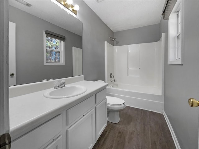 bathroom featuring toilet, wood finished floors, vanity, baseboards, and shower / bathtub combination