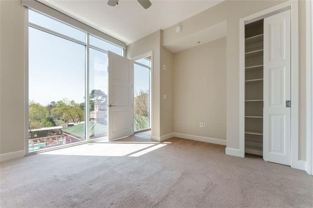 carpeted empty room featuring baseboards and a ceiling fan