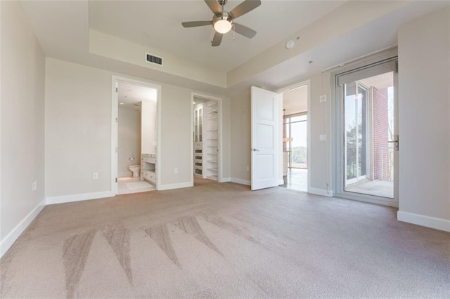 unfurnished bedroom featuring access to exterior, carpet flooring, a walk in closet, baseboards, and visible vents