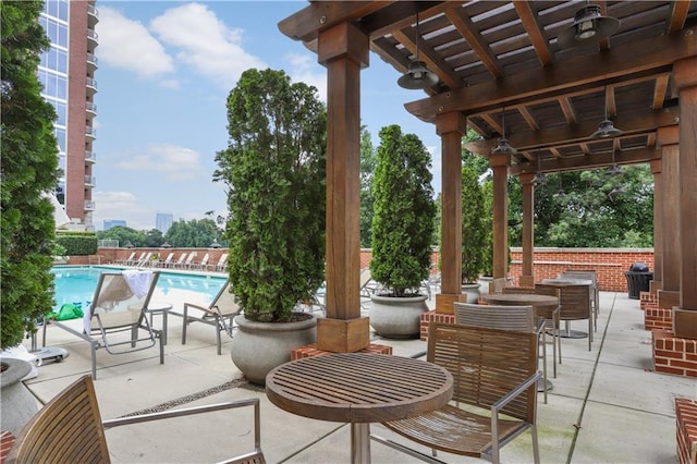 view of patio with a community pool, a pergola, and outdoor dining space