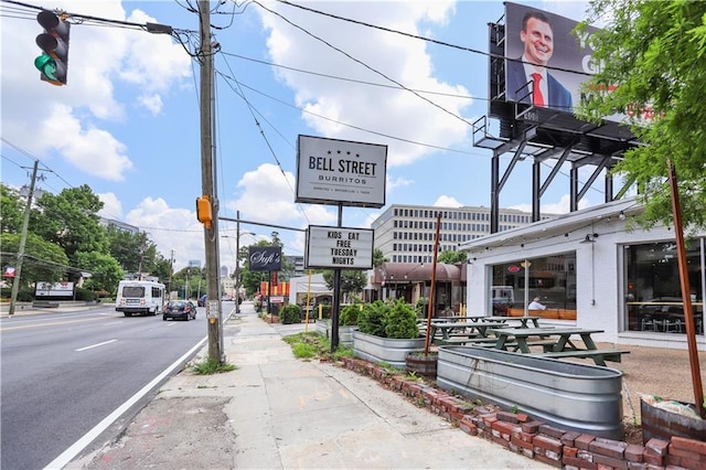 view of street featuring curbs, sidewalks, traffic lights, traffic signs, and street lighting