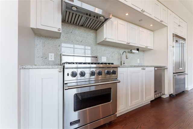 kitchen with white cabinetry, backsplash, high quality appliances, and range hood