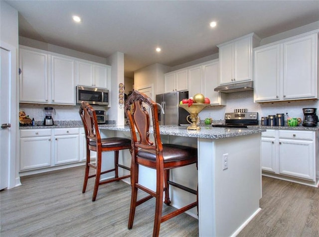 kitchen with a kitchen island, appliances with stainless steel finishes, a breakfast bar area, and white cabinets