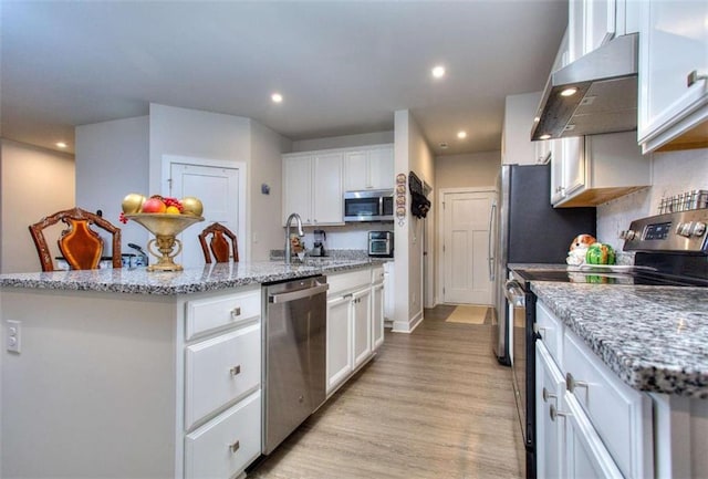 kitchen with sink, a center island with sink, wall chimney range hood, stainless steel appliances, and white cabinets