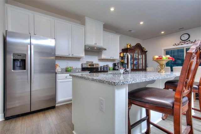 kitchen with white cabinetry, appliances with stainless steel finishes, a breakfast bar, and a kitchen island with sink