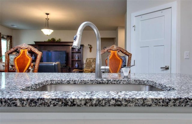 room details featuring stone countertops, decorative light fixtures, and sink