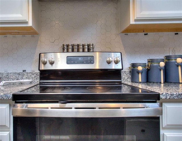 interior details featuring electric stove, light stone counters, tasteful backsplash, and white cabinets