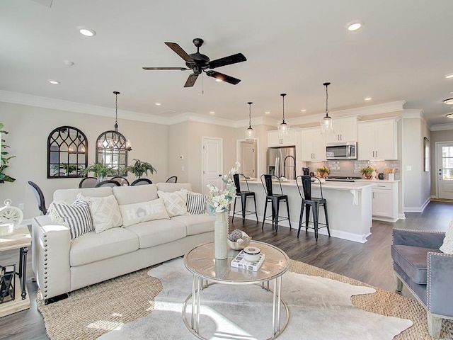 living room featuring hardwood / wood-style floors, crown molding, and ceiling fan with notable chandelier