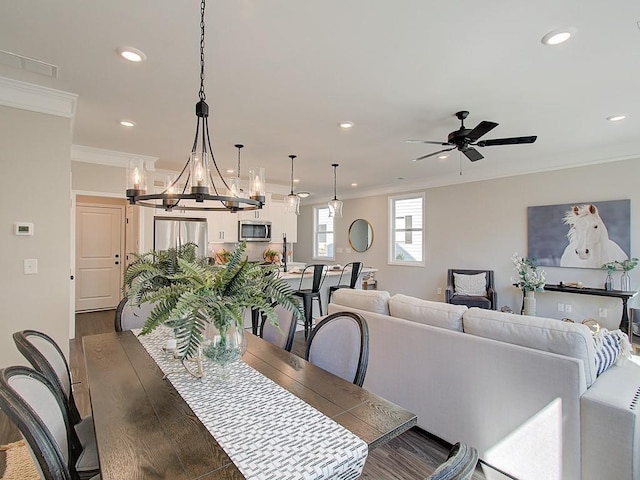 dining space with crown molding, dark wood-type flooring, and ceiling fan with notable chandelier