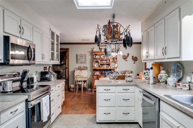 kitchen with kitchen peninsula, sink, white cabinets, and appliances with stainless steel finishes