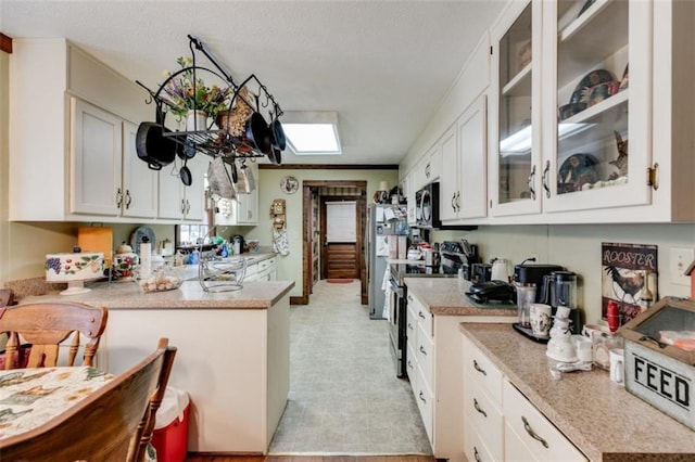 kitchen featuring a skylight, crown molding, white cabinets, and appliances with stainless steel finishes