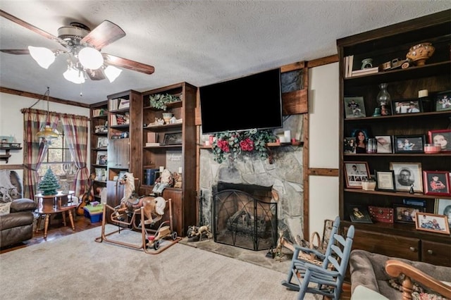 living room with a fireplace, ceiling fan, carpet floors, and a textured ceiling