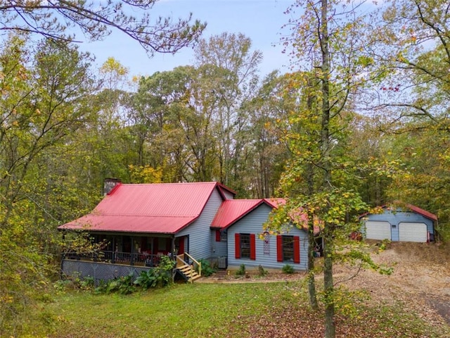 view of front facade with a front yard, a porch, a garage, and an outdoor structure