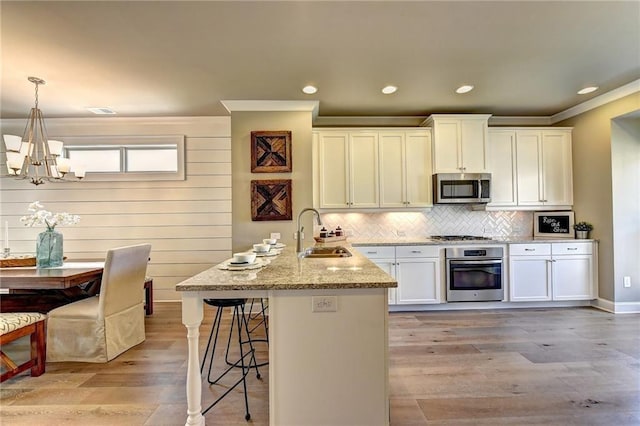 kitchen featuring a kitchen bar, a peninsula, a chandelier, a sink, and stainless steel appliances