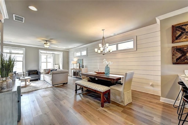 dining space featuring light wood finished floors, baseboards, ornamental molding, and visible vents