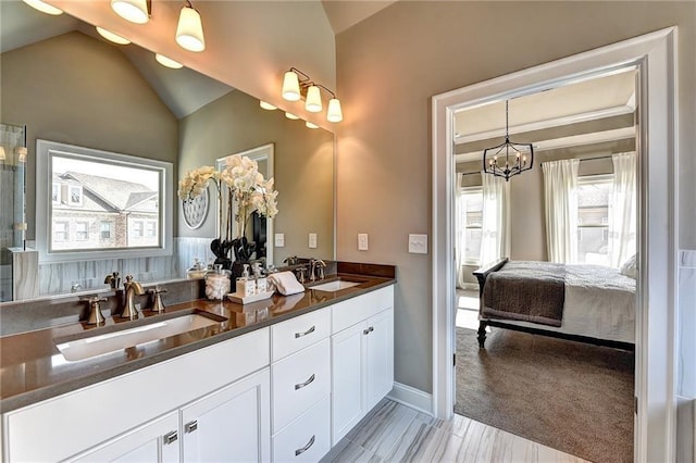 ensuite bathroom with a sink, double vanity, connected bathroom, and lofted ceiling