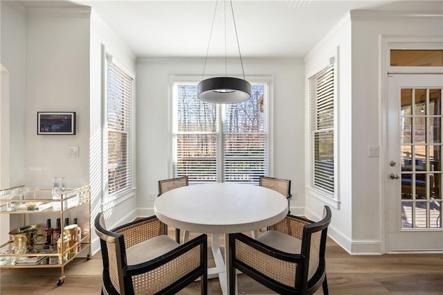 dining area with wood finished floors, baseboards, and ornamental molding