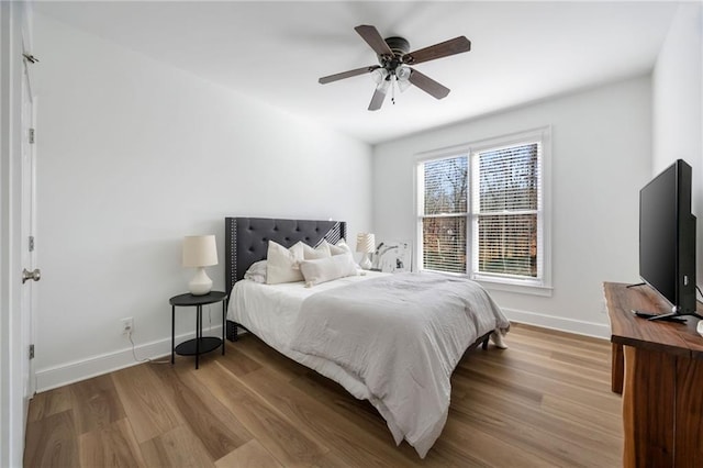 bedroom featuring baseboards, wood finished floors, and a ceiling fan
