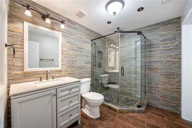 bathroom featuring tile walls, toilet, a stall shower, and wood finished floors